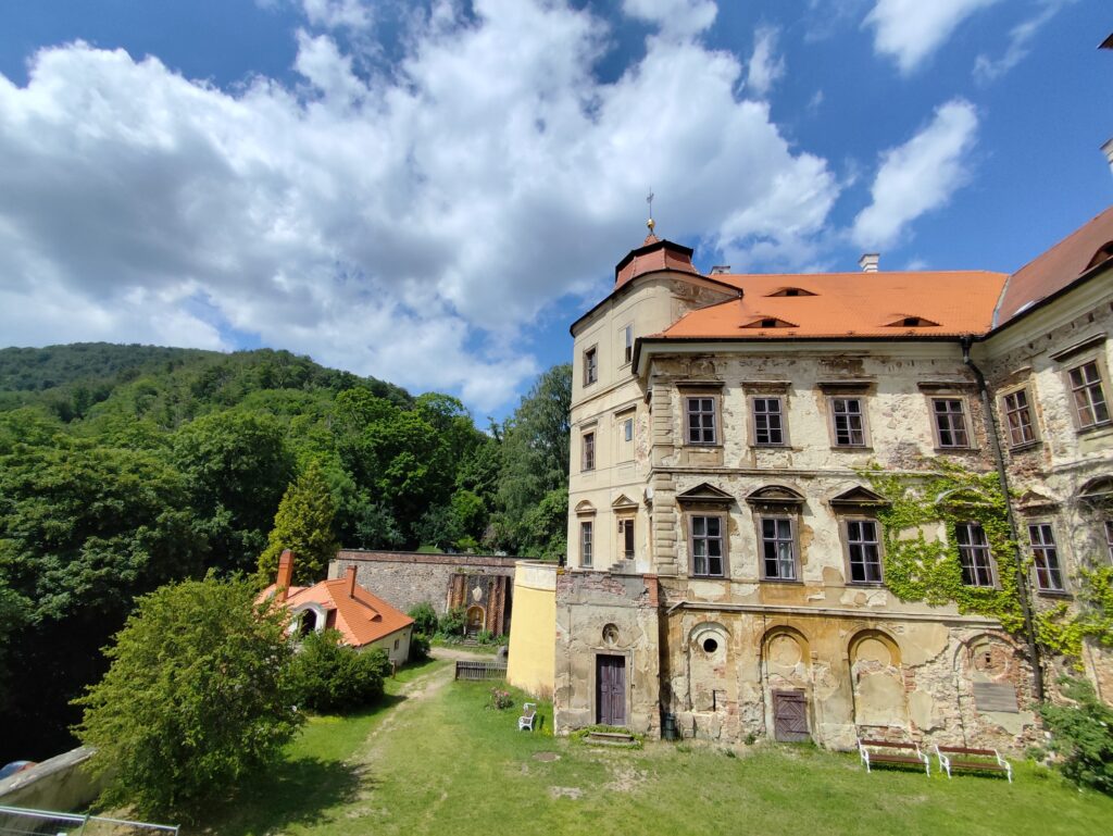 Historické krídlo zámku Jezeří obklopené zeleňou na úpätí Krušných hôr